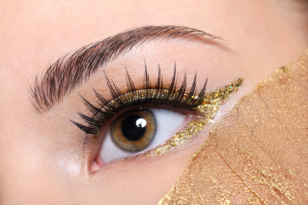 macro shot woman eye with false eyelashes yellow golden make up