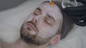 close up male hands in gloves applying moisturizing facial cream