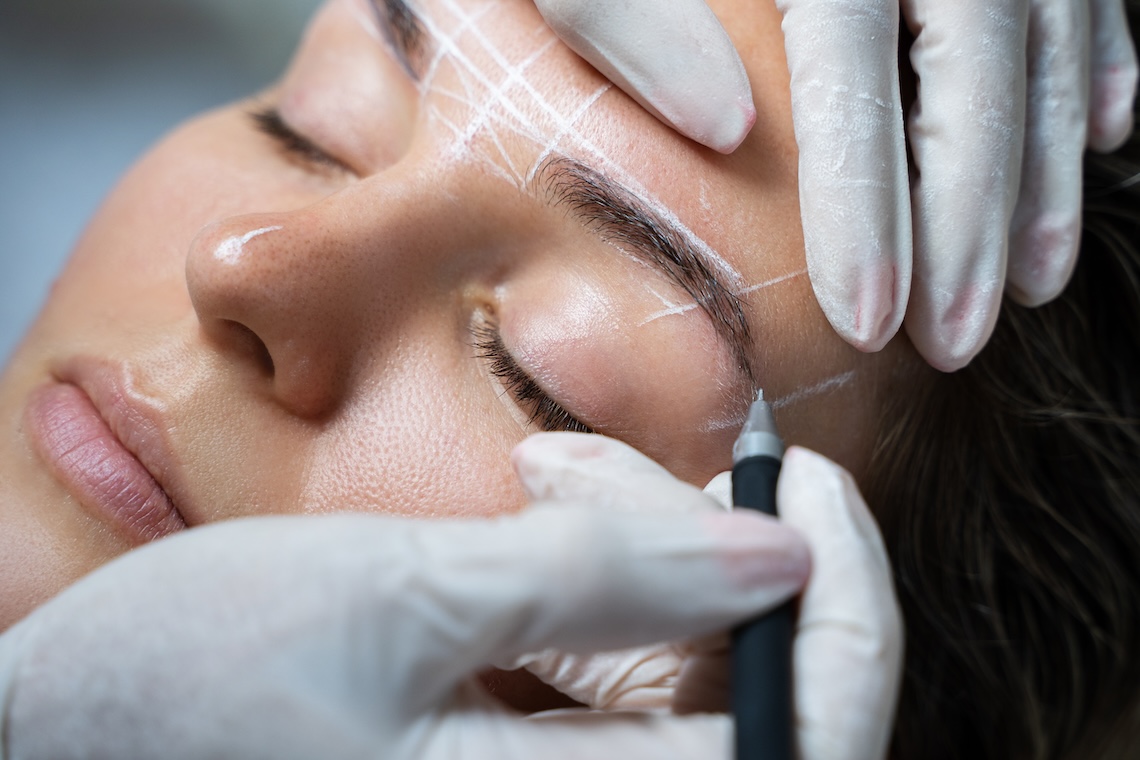 Young woman during professional eyebrow mapping procedure before permanent makeup