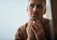 Close up portrait of attractive young gentleman touching his chin while checking skin condition. Copy space in left side